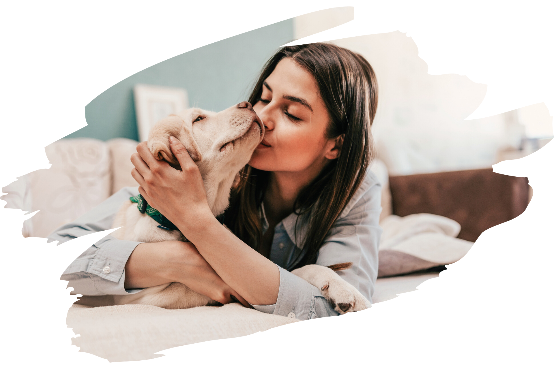A woman hugging and kissing a light-colored puppy on a couch